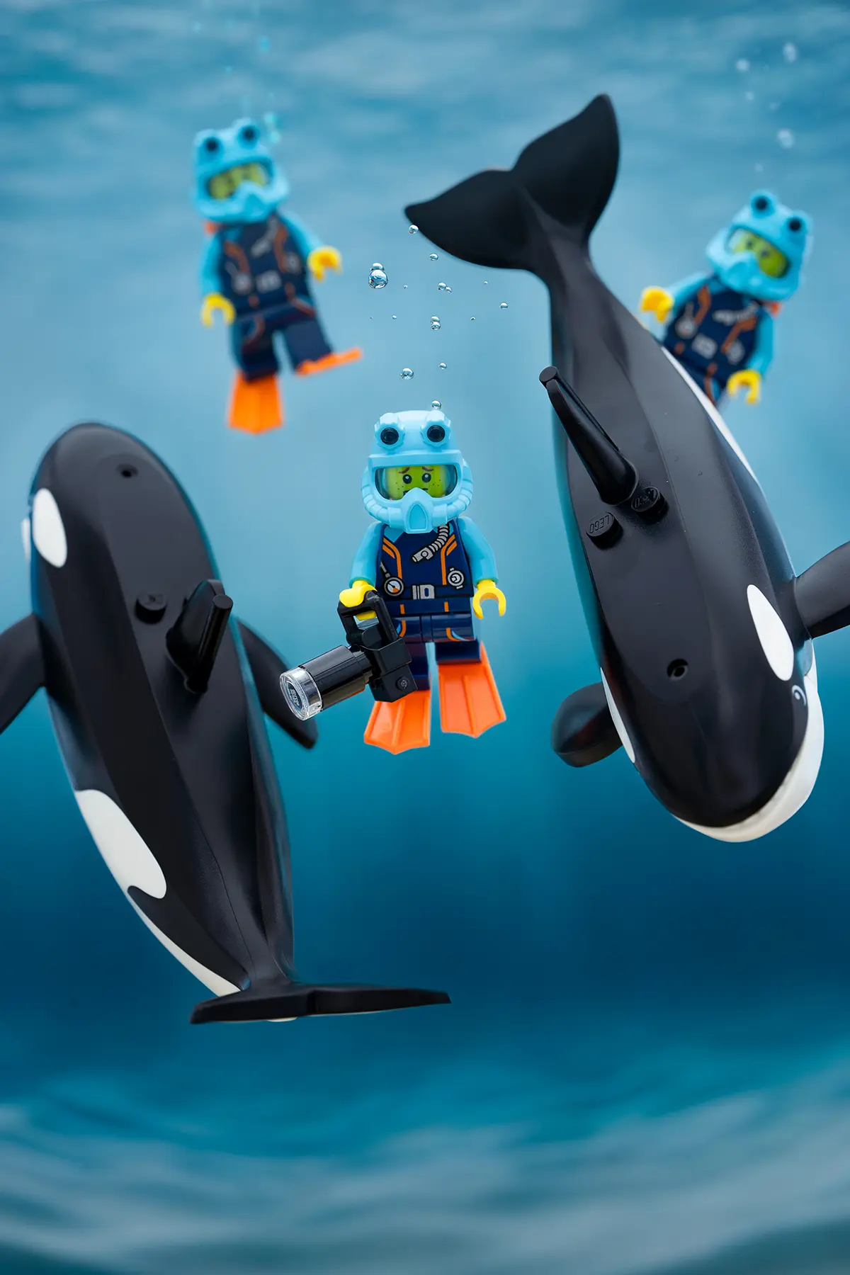 LEGO scuba divers and orcas appear to float naturally underwater with added air bubbles and removed Support bars, creating a seamless and immersive ocean scene with vibrant lighting and a clear sense of depth.